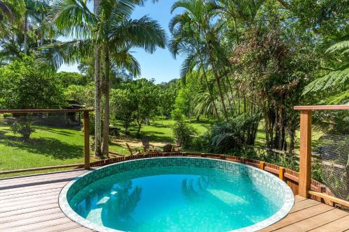a swimming pool on a wooden deck with palm trees at Figtree Creek Retreat in The Pocket
