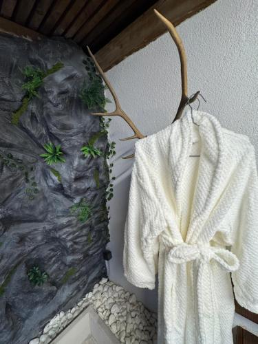 a white robe hanging on a wall with a painting at Studio Nessa with a private jacuzzi in Krk