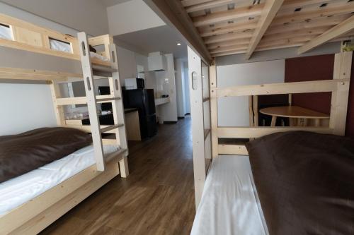 a room with two bunk beds and a desk at ミチ旅ホテル 読谷 in Yomitan