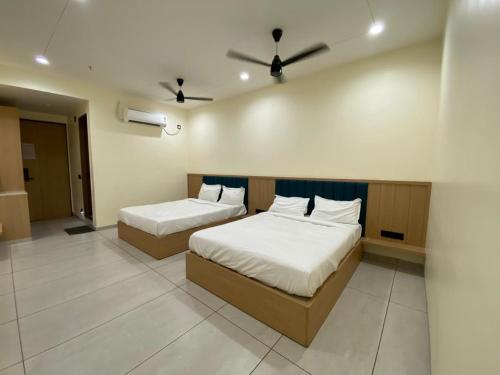 a bedroom with two beds and a ceiling fan at Mahadev Hotel in Botād