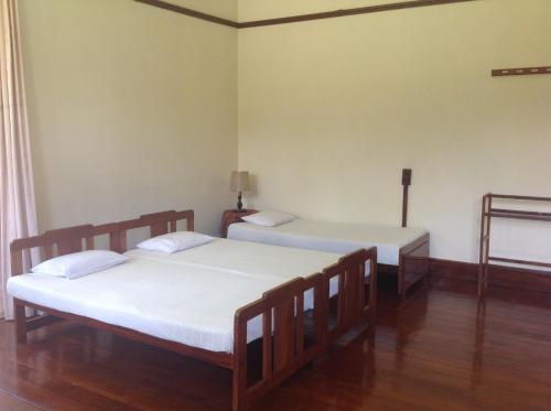 due letti in una stanza con pavimenti in legno di Morris Bungalow a Passara