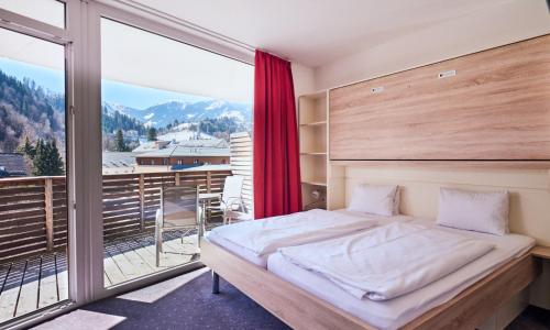 a bedroom with a bed and a large window at Hotel Planai by Alpeffect Hotels in Schladming