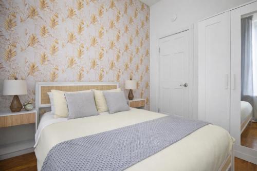 a bedroom with a white bed with a floral wallpaper at Classy 2BD Home in Manhattan in New York
