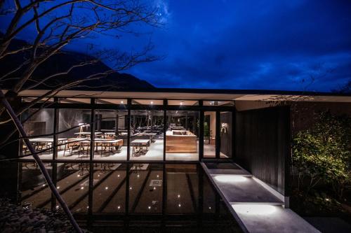 a glass house with a deck at night at Hotel MODA in Yufu