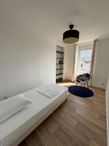 a white bedroom with a bed and a chair at L' Annexe Barneville Bourg in Barneville-Carteret