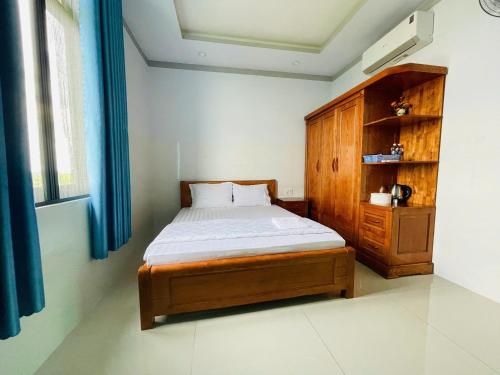 a bedroom with a bed and a wooden cabinet at Hotel Trâm Anh 1 in Nhơn Trạch