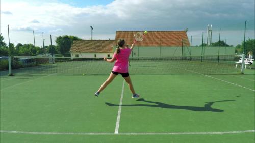 a woman hitting a tennis ball on a tennis court at Camping Le Walric in Saint-Valery-sur-Somme