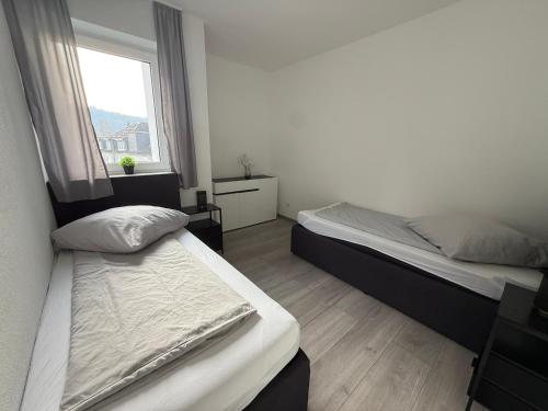 two beds in a room with a window at Sauerland Wellness Apartment mit Sauna und Jacuzzi in Olpe