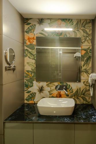 a bathroom with a sink and a mirror at Hotel Sky International in Kizhake Chālakudi