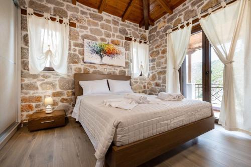 a bedroom with a large bed and a stone wall at Elevi Aria in Tyros