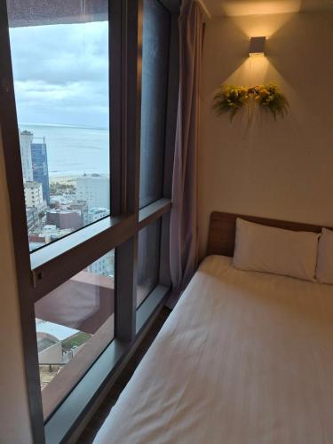 a bed in a room with a large window at Haeon stay haeundae in Ch'ŏngsap'o