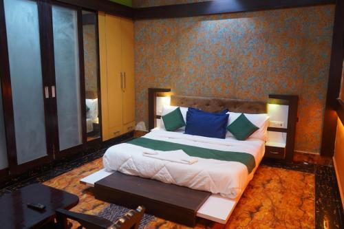 a bedroom with a large bed with blue and green pillows at Hotel Konaaz Inn in Alīgarh