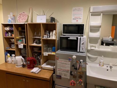 a kitchen with a microwave on top of a refrigerator at Tsukiji Hostel Wakayama 2 in Wakayama