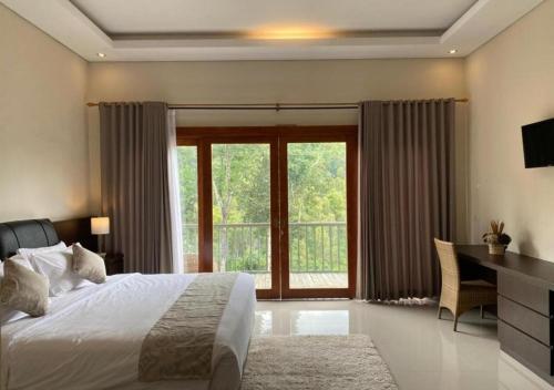 a bedroom with a bed and a desk and a window at Nadira BnB in Munduk