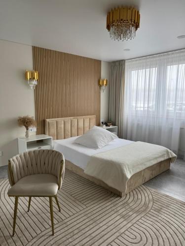 a bedroom with a large bed and a chair at Baltic Avenue Duo in Klaipėda