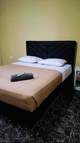 a bed with a black headboard and white pillows at Hotel Permata Inn Ball Room Seroja in Kualakapuas