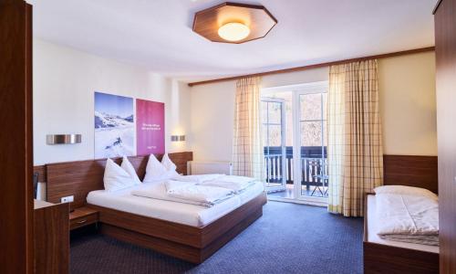 a hotel room with a bed and a balcony at Hotel Pinzgauerhof by Alpeffect Hotels in Zell am See