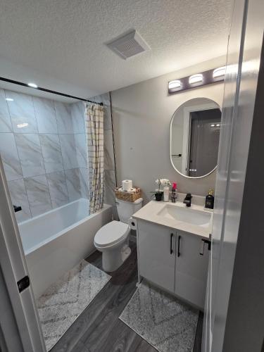 a bathroom with a sink and a toilet and a mirror at Cozy 2 Bedroom basement Suite in Calgary