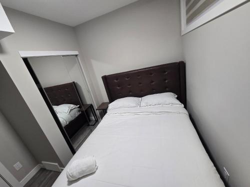 a small bedroom with a bed and a mirror at Cozy 2 Bedroom basement Suite in Calgary