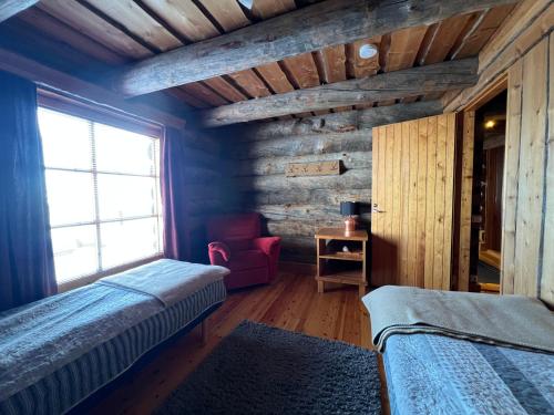 a bedroom with two beds and a chair and a window at Riihilinna Ski Lodge in Muurame