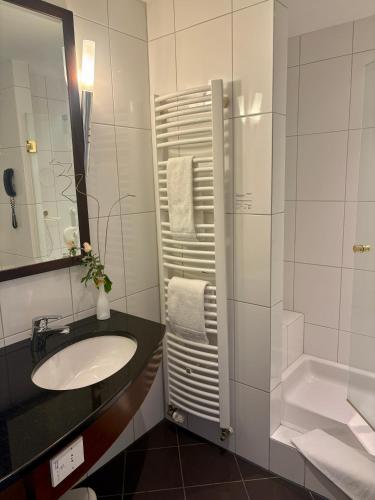 a white bathroom with a sink and a shower at Akzent Hotel Höltje in Verden