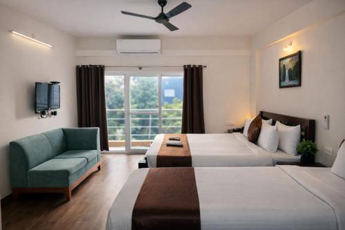 a hotel room with two beds and a chair and a window at Coffee Bean Inn in Bangalore