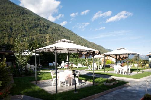 a patio with white chairs and umbrellas at Hotel Michela in Malè
