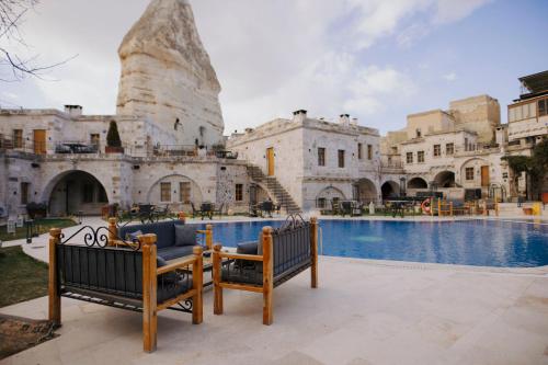 a pool with two benches in front of a building at Göreme Cave Suites in Göreme