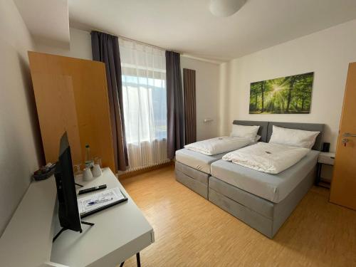 a living room with a bed and a table with a tv at Klosterhof Neustadt am Main in Neustadt am Main