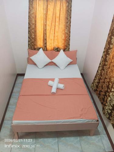 a bed with two pillows on it with at Buena Lynnes Annex Lodge in Puerto Galera