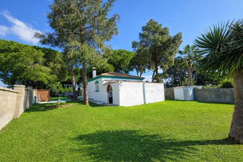 a small white house in a yard with trees at Chalet Amanecer Chiclana in Novo Sancti Petri