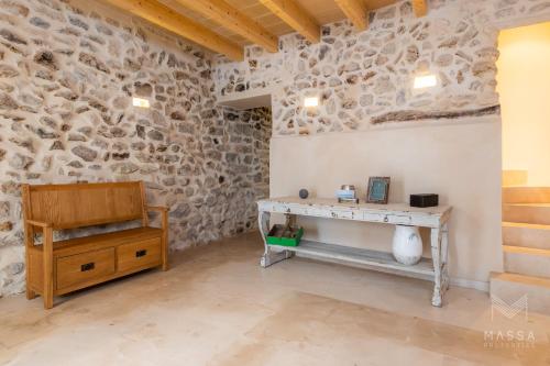 a room with a stone wall with a table and a bench at Casa Abeurador, con mucho encanto en el centro de Artà in Artá