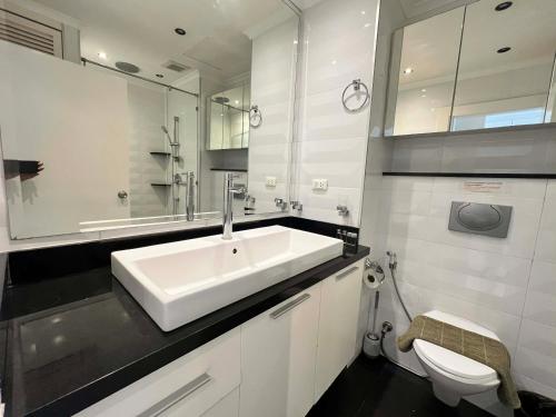 a white bathroom with a sink and a toilet at Viewtalay Beachfront by ND in Pattaya South