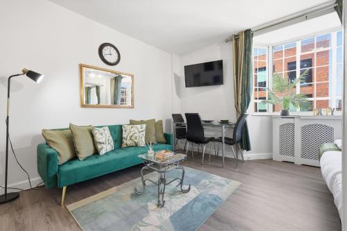 a living room with a green couch and a table at The Kensington Luxe Residence - Elite Location in London