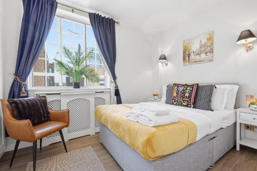a bedroom with a bed and a chair and a window at The Kensington Luxe Residence - Elite Location in London