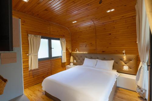 a bedroom with a white bed in a wooden room at Sim Forest Resort in Phú Quốc