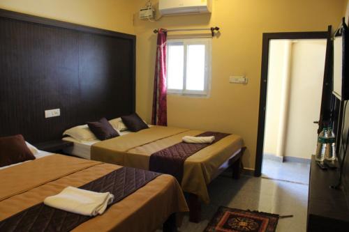 a hotel room with two beds and a window at GSR RESIDENCy in Kanchipuram