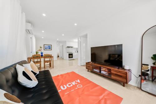 a living room with a black couch and a television at B2 Airport Adjacent Home - New Amenities & Fast Wi-Fi in Perth