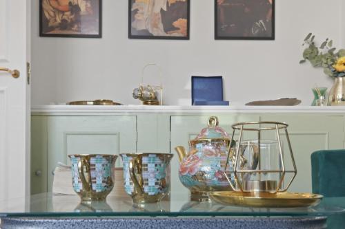 a glass table with three cups and a vase on it at Luxury Kensington Apt - Walk to Harrods in London