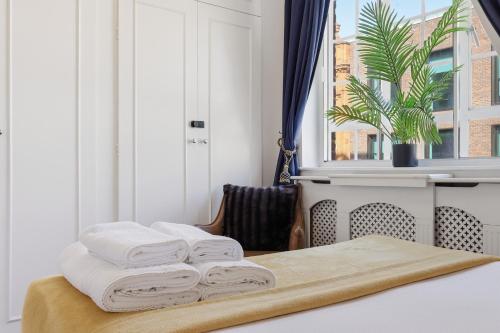 three towels stacked on a table in a room with a window at Luxury Kensington Apt - Walk to Harrods in London