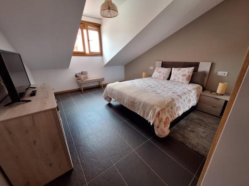 a bedroom with a bed and a flat screen tv at Aldea Bricia 20 BC in Posada de Llanes