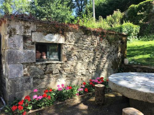 a stone wall with flowers and a window at Moulin de la Fayolle in Blot-lʼÉglise