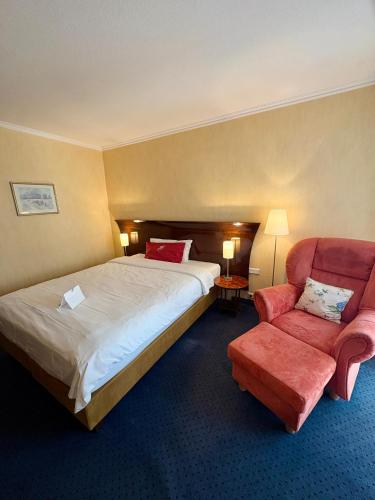 a hotel room with a bed and a red chair at Akzent Hotel Höltje in Verden