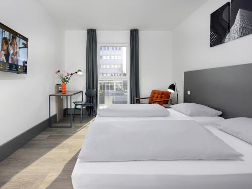 a hotel room with two beds and a desk at smartments Frankfurt City-Ost in Frankfurt