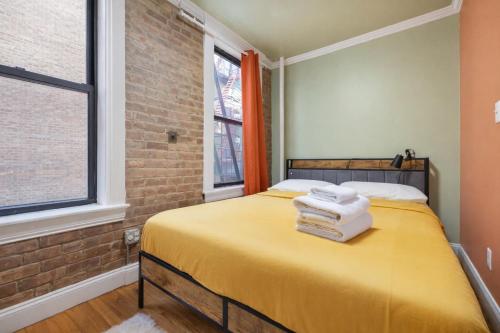 a bedroom with a yellow bed with towels on it at 2 Bedroom Home Unit In Lower Manhattan in New York