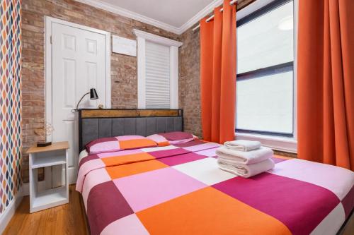 a bedroom with a bed and a window with orange curtains at 2 Bedroom Home Unit In Lower Manhattan in New York