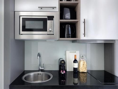 a kitchen counter with a microwave and a sink at smartments Frankfurt City-Ost in Frankfurt