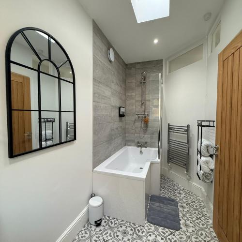 a bathroom with a tub and a sink and a mirror at 171 Stroud Road in Gloucestershire
