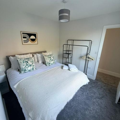 a bedroom with a large bed with white sheets and pillows at 171 Stroud Road in Gloucestershire