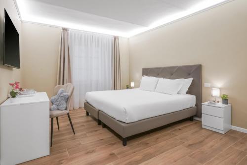 a bedroom with a large white bed and a chair at B&B Le Stanze del Duomo in Florence